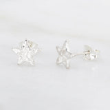 chunky 8mm textured star stud earrings on a marble background