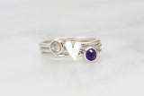 Sterling silver 8 mm elongated hammered heart ring stacked between a  4 mm labradorite and 4 mm amethyst gemstone ring.